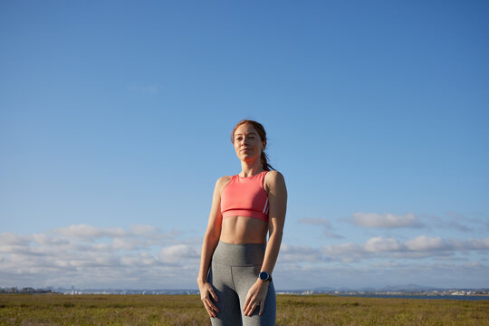 Redhead woman in fitness wear posing to camera in an outdoor environment