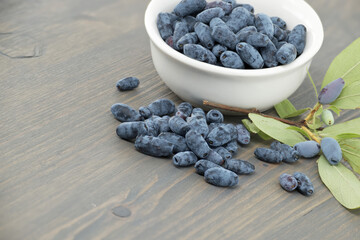 White bowl filled with Honeyberry haskap berries on wooden table