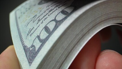 A close-up of hands counting US 100 bills, evoking a timeless sense of wealth and luxury. Cash flow...