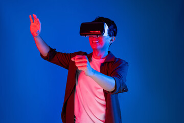 Smart gamer wearing VR turning to metaverse new world driving in car racing competition game player isolated blue neon light wall connected futuristic technology virtual reality meta. Contrivance.