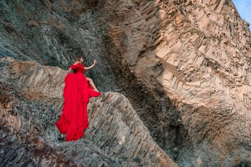 woman sea red dress. Woman with long hair on a sunny seashore in a red flowing dress, back view,...