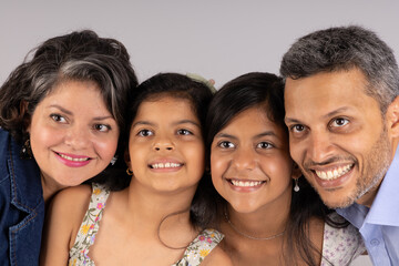 A family of four, a man and three girls, are smiling and posing for a picture