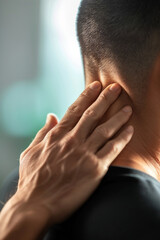 Fototapeta premium Close-up of person touching their neck, illustrating pain or discomfort. Focus on hand and neck in soothing environment.