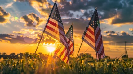 Vibrant American flags standing tall in a grassy field at sunset, the sky ablaze with orange hues, capturing Memorial Day's solemn beauty