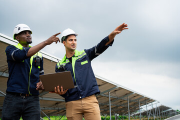 Two men in construction gear are pointing at a laptop. One of them is wearing a green jacket