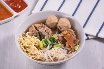 Meatballs or Bakso, one of Indonesian specialties. Served with yellow noodles, vermicelli and vegetables in a white bowl