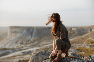 Woman admiring breathtaking view from cliff edge with windblown hair, embodying wanderlust and...