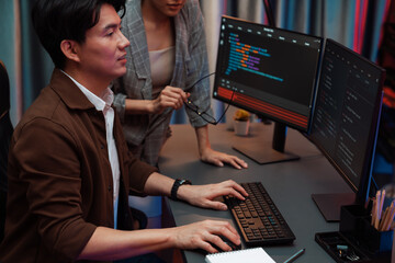 IT developers discussing with point to intelligent website development coder system running data online two screens information technology at neon light room at modern office. Infobahn.