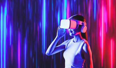 Smart female standing surrounded by neon light wearing VR headset connecting metaverse, future...