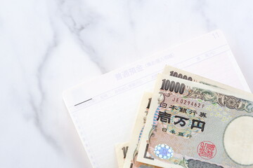 テーブルの上に開いた状態で置かれた銀行の預金通帳と、1万円札
