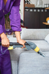 vertical shot of a woman cleaning a couch with her steam cleaner.