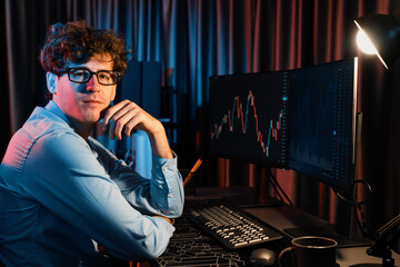 Profile of young investor stock in trader looking at camera with dynamic exchange rate in screens...