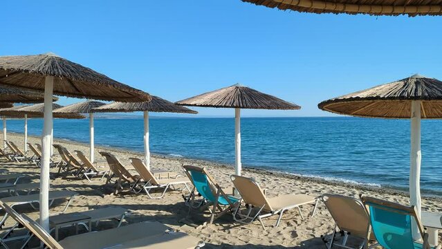Lounge chairs and straw  umbrellas at Olimpic Riviera, beach - Greece 