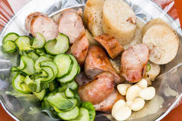 Close-up of Taiwanese sausage and sticky rice (glutinous rice) sausage on a plate, with some garlic and cucumber. This is one of the street snacks popular among tourists in Taiwan.