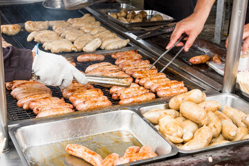 Close-up of the vendors are grilling Taiwanese sausage and sticky rice (glutinous rice) sausage in the night market of Taiwan. This is one of the street snacks popular among tourists in Taiwan.