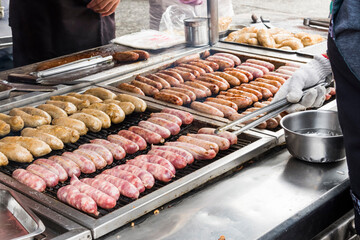 Close-up of the vendors are grilling Taiwanese sausage and sticky rice (glutinous rice) sausage in the night market of Taiwan. This is one of the street snacks popular among tourists in Taiwan.