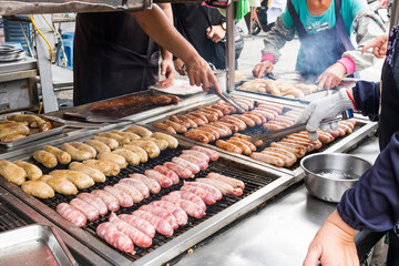 Close-up of the vendors are grilling Taiwanese sausage and sticky rice (glutinous rice) sausage in the night market of Taiwan. This is one of the street snacks popular among tourists in Taiwan.