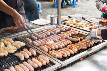 Close-up of the vendors grilling Taiwanese sausage and sticky rice (glutinous rice) sausage in the night market in Taiwan. This is one of the street snacks popular among tourists in Taiwan.