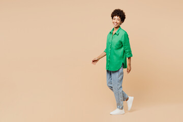 Full body side profile view fun young woman of African American ethnicity wear green shirt casual...