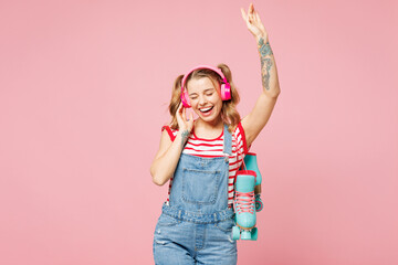 Young excited woman she wear red t-shirt denim overalls casual clothes hold blue rollers listen to...