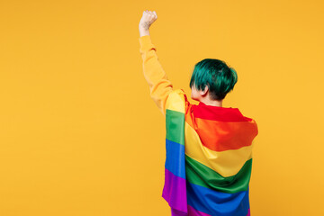 Back rear side view young lesbian woman with dyed green hair wrapped in rainbow striped flag...