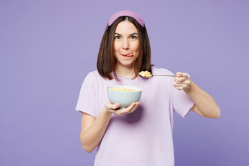 Young happy woman wear pyjamas jam sleep eye mask rest relax at home eat breakfast muesli cereals...