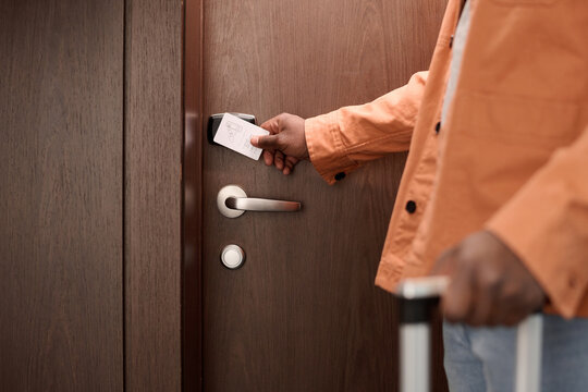 Close up of guest opening hotel room door and pressing keycard to NFC security lock system copy space