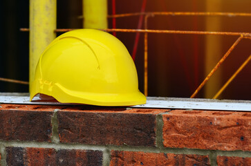 Yellow hard hat on top of red brick wall