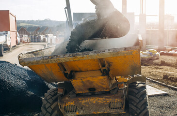 Fresh hot asphalt delivered on building site for new road construction