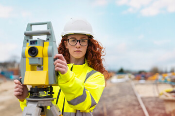 concentrated apprenticeship female site engineer surveyor working with theodolite EDM equipment at...