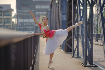 Beautiful girl ballerina dancing. Ballerina Performance Street Show in the city. A teenager poses...