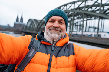 happy elderly mature man enjoying life at full by traveling around world taking selfies in Germany ...