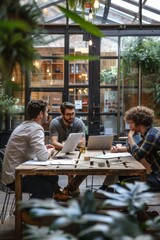 Fototapeta premium Three men are sitting around a wooden table in a greenhouse