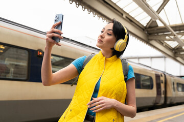 cheerful  female using phone taking selfie at train station Safety travel concept	