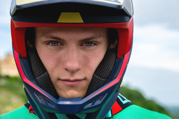 Close-up portrait of a confident handsome young athlete wearing a stylish helmet looking at the...