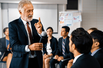 Senior leader speaker speaks to public people audience in training workshop or conference. Mature...