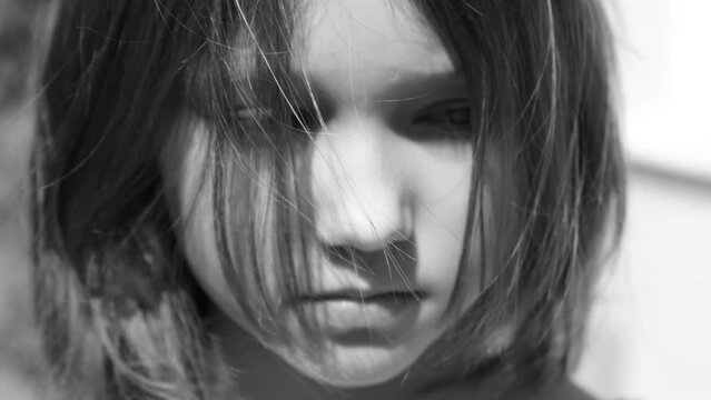A 9-10 year old girl, or a teenager, stands on the street with her hair flying, black and white video, Bullying concept, teenagers with mental health problems, resentment, stress, misunderstanding