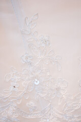 Detailed close-up of intricate white lace patterns on a bridal gown, showcasing elegance and craftsmanship.
