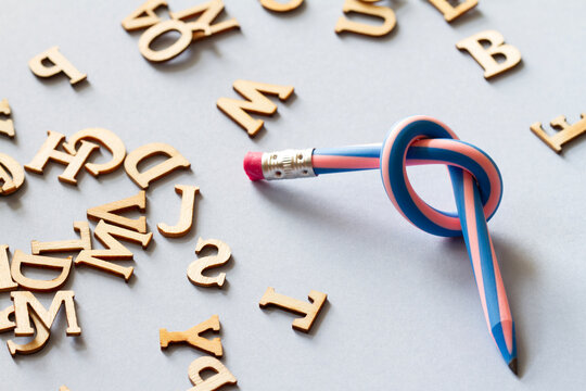 Pencil with knot and scattered letters, dyslexia concept