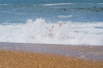 A man drowns in a wave near the shore at Nazaré Beach in Portugal in the summer.