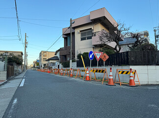 construction, traffic cones, street signs, and barricades on an old residential neighborhood street...