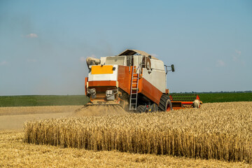 Combine harvester at work on a wheat field under a clear blue sky