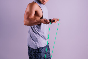Man in grey tank top holds green jump rope with wrist