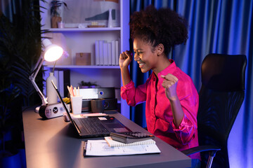 African woman blogger wearing pink shirt with happy face, looking on screen laptop with valued...