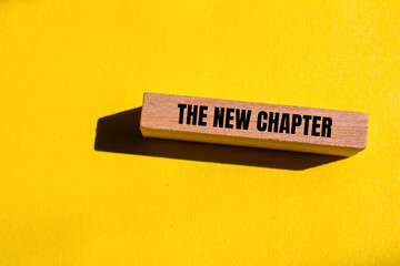 The new chapter words written on wooden block with yellow background. Conceptual the new chapter...