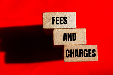 Fees and charges words written on wooden blocks with red background. Conceptual fees and charges...