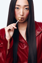 Young woman with long black hair and red jacket brushing her teeth with a toothbrush