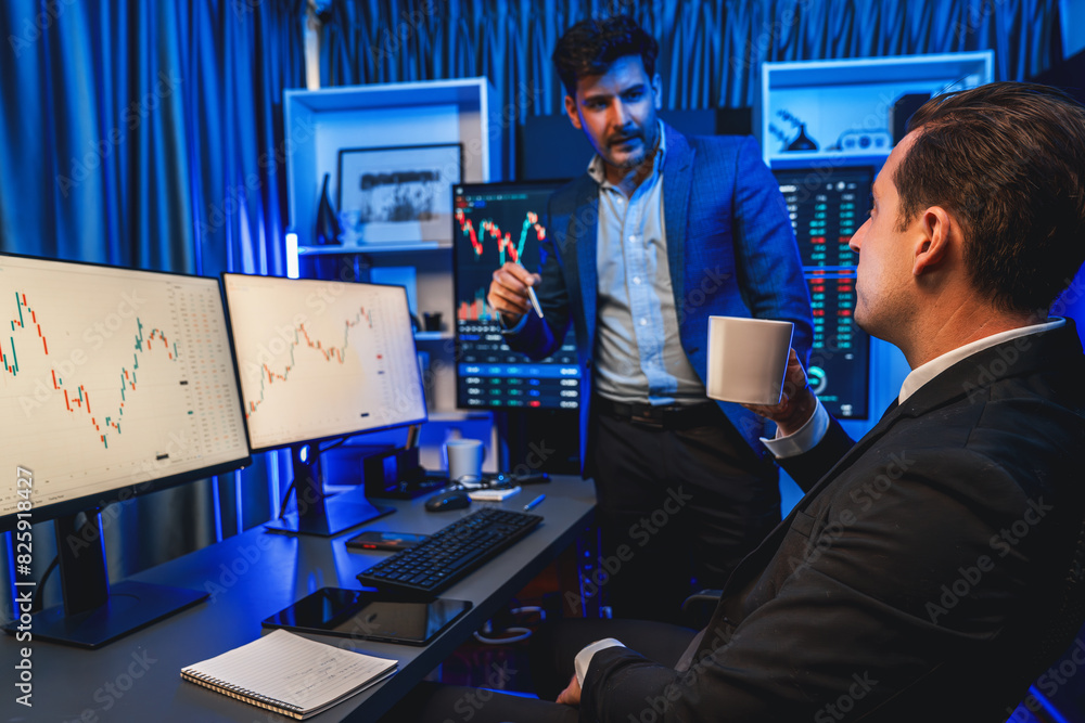 Poster two stock exchange traders discussing dynamic investment graph in currency rate on monitor at night.