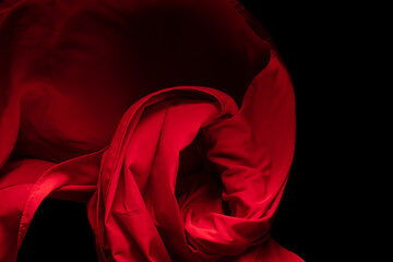 Red Cotton fabric flying in curve shape, Piece of textile Red cotton fabric throw fall in air. Black background isolated, dark shading environment