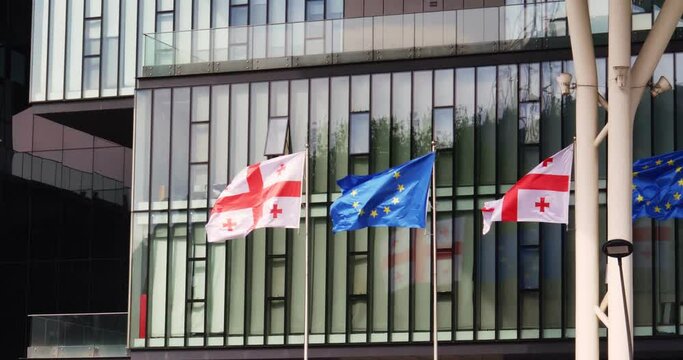 The EU and Georgian flags flutter against the background of the glass facade of the building. The path to the loss of state sovereignty.